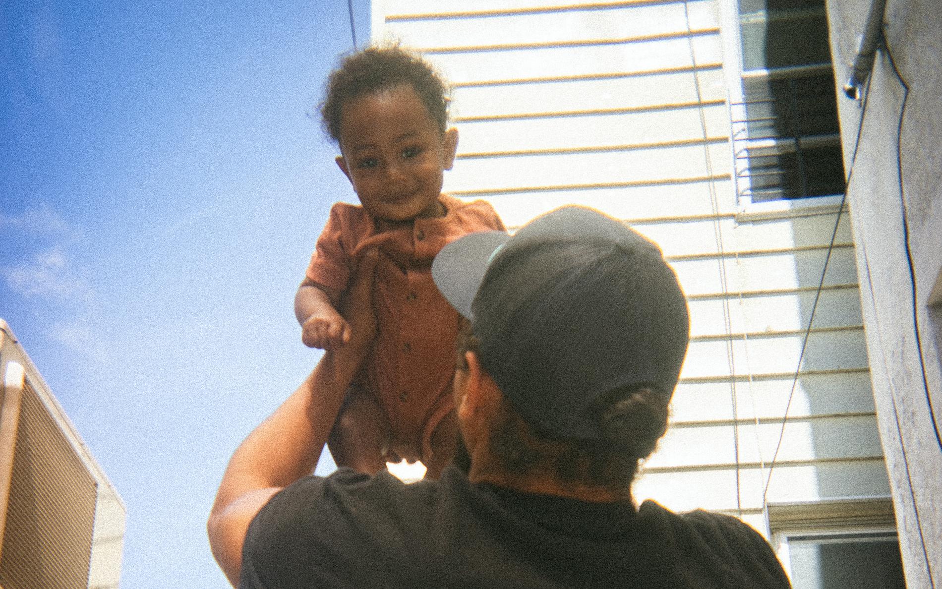 Lifting Tommy up outside the shop on a clear afternoon