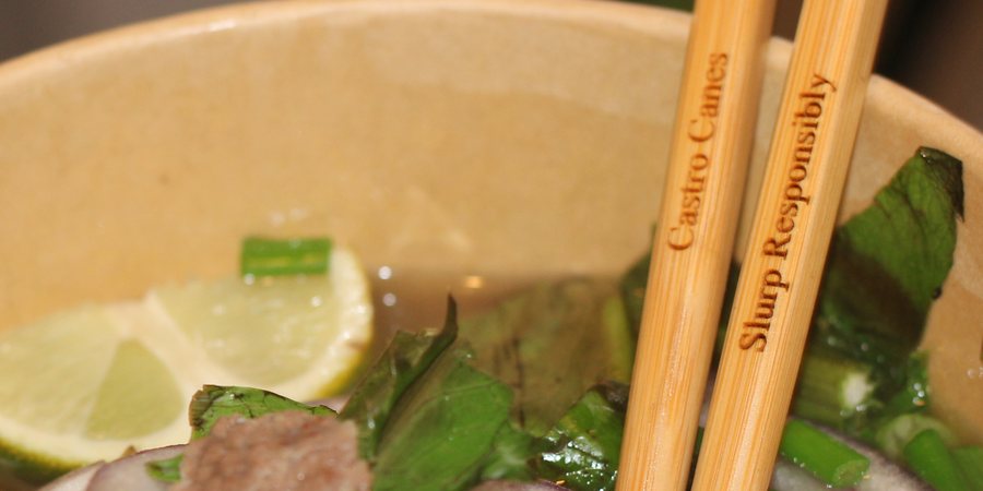Engraved Castro Canes bamboo chopsticks resting in a bowl of pho