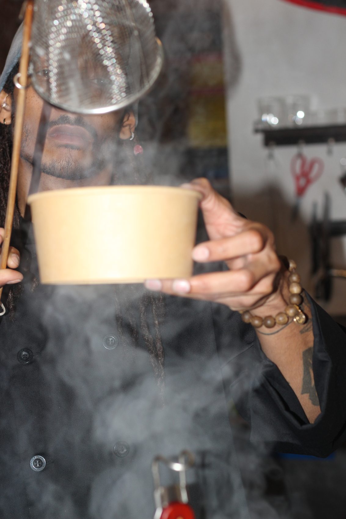 A bowl of pho lifted into rising steam at the pop-up