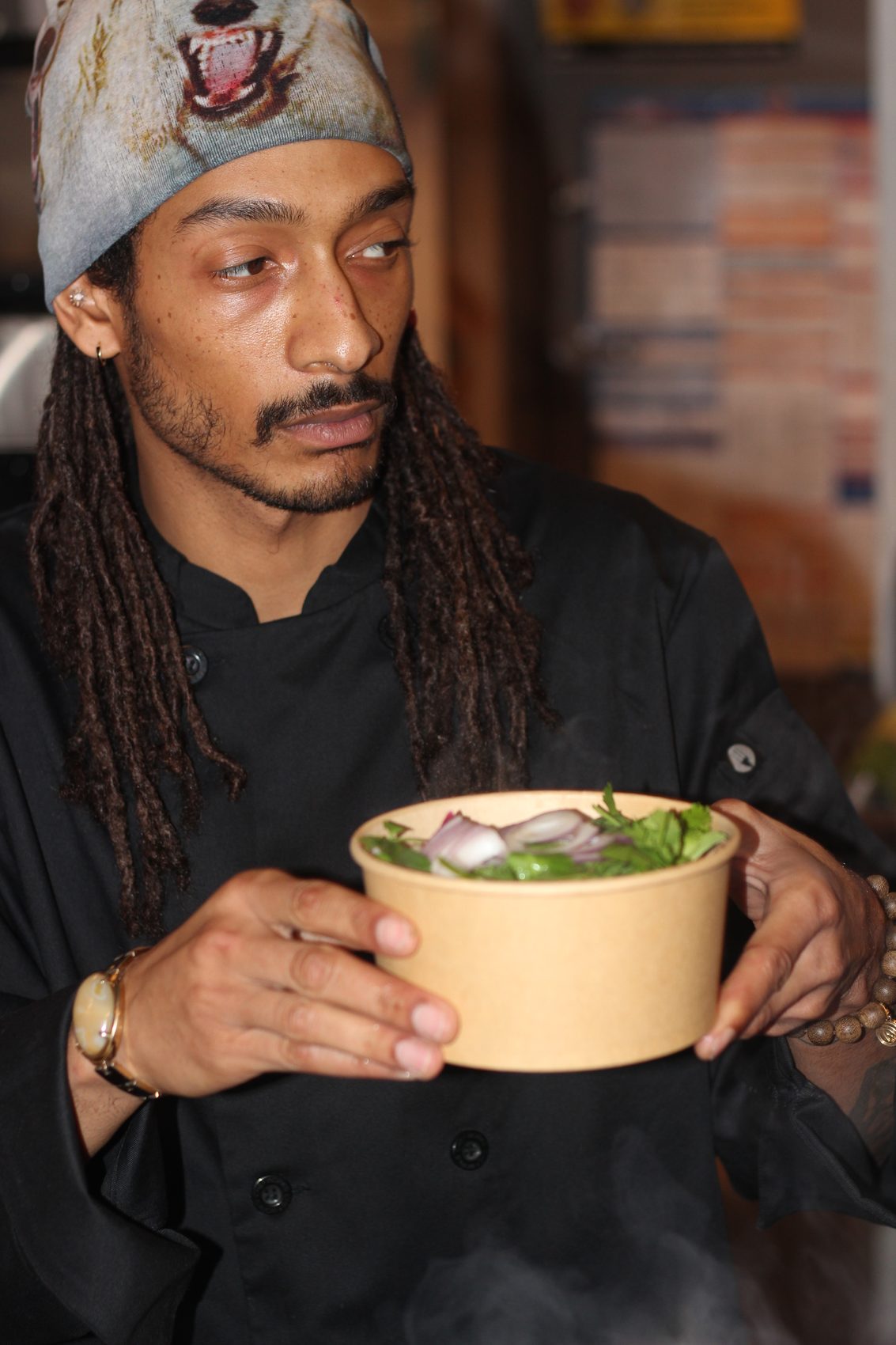 The cook cradling a bowl of pho through the steam